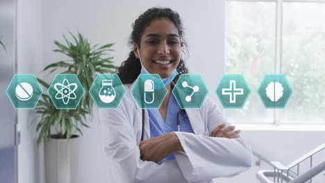 female doctor crossing arms in clinic, showcasing floating hex medical icons around stethoscope