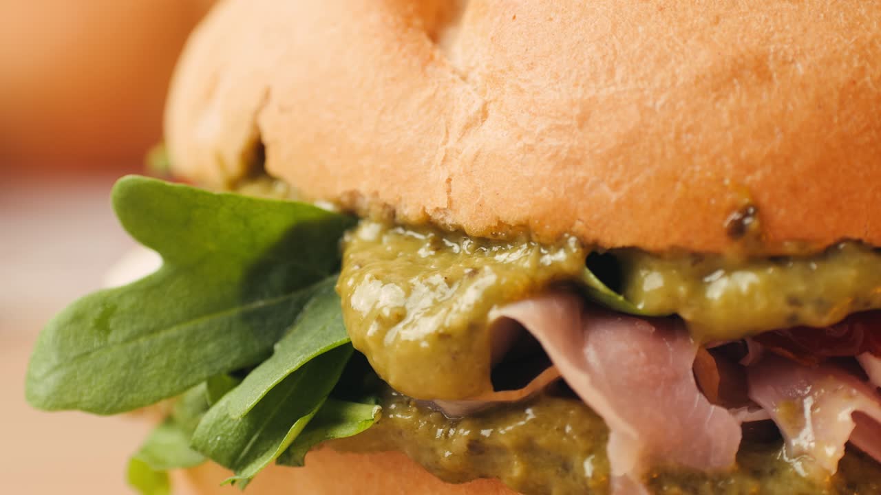 Mortadella ham sandwich, Traditional italian focaccia filled with thin pesto slices of mortadella, served by chef man in cafe restaurant. Macro of traditional italian spanish tapas antipasti.