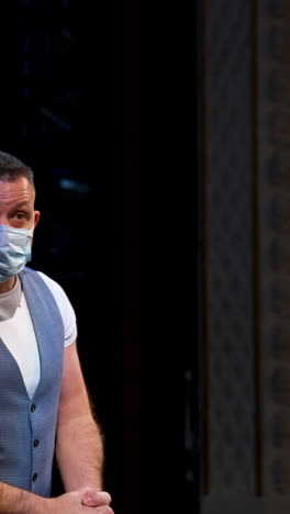 man in medical mask on scene. actor in protective mask is talking and gesticulating a lot while standing on stage in the theater. pandemic in the world. vertical video
