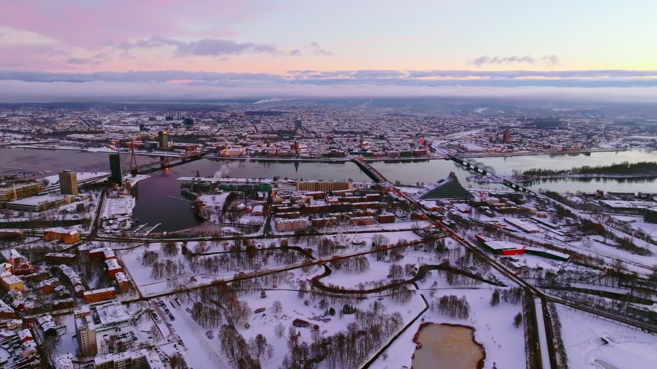 Majestic wide drone view of Riga at sunrise, snow-covered winter cityscape, 4K