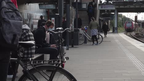 woman in medical mask holding bike and walking on train station, outdoors