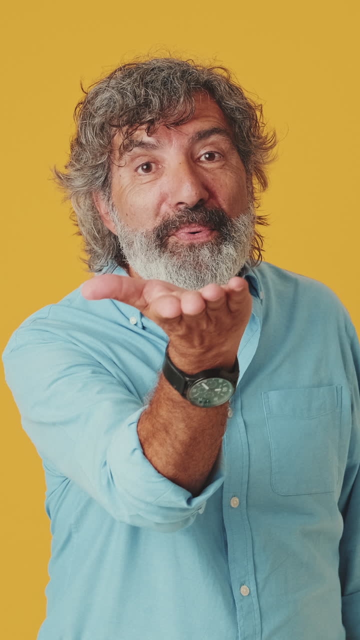 Uomo maturo che manda un bacio e sorride su sfondo giallo