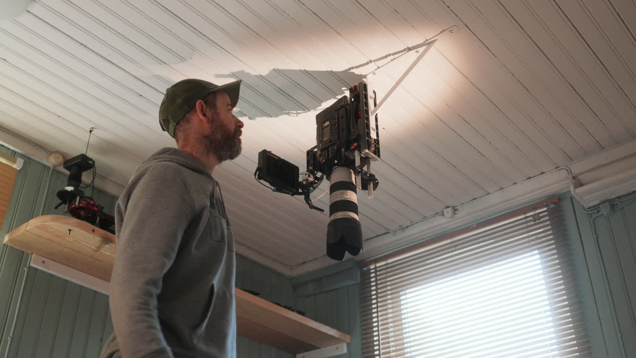 Man installs and mounts cinema camera to ceiling bracket for top down view