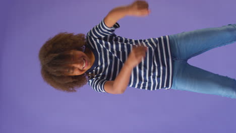 studio shot of boy having fun dancing against purple background