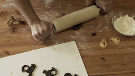 hands roll and make gingerbread from dough and lay on sheet, high angle