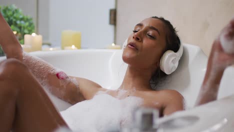 Mixed-race-woman-lying-in-a-bathtub-at-home