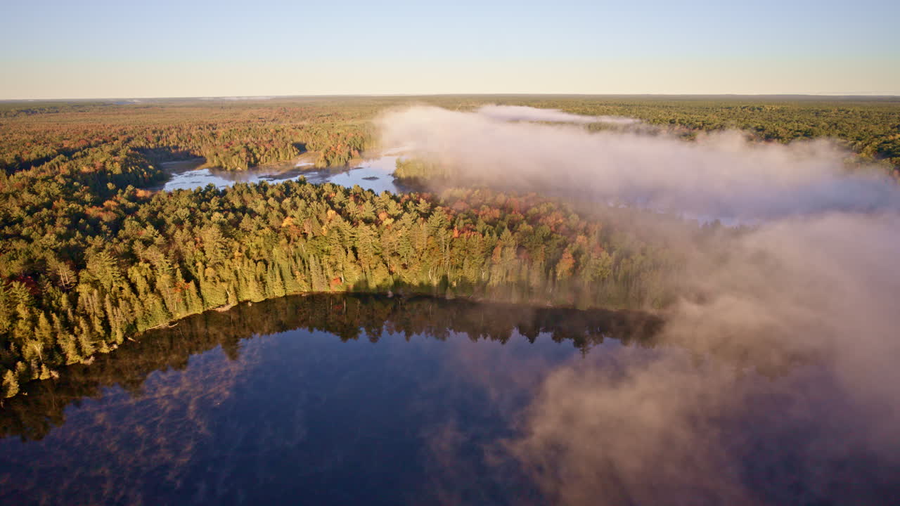 Cinematic morning drone shot of mist lifting across the water