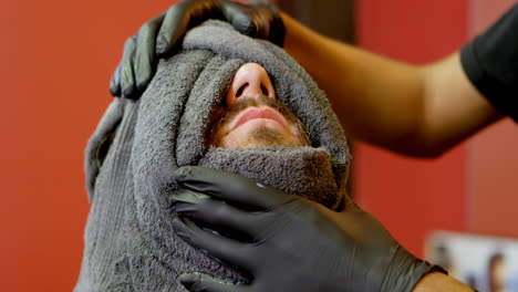 barbero envolviendo la cara del hombre en una toalla caliente 4k