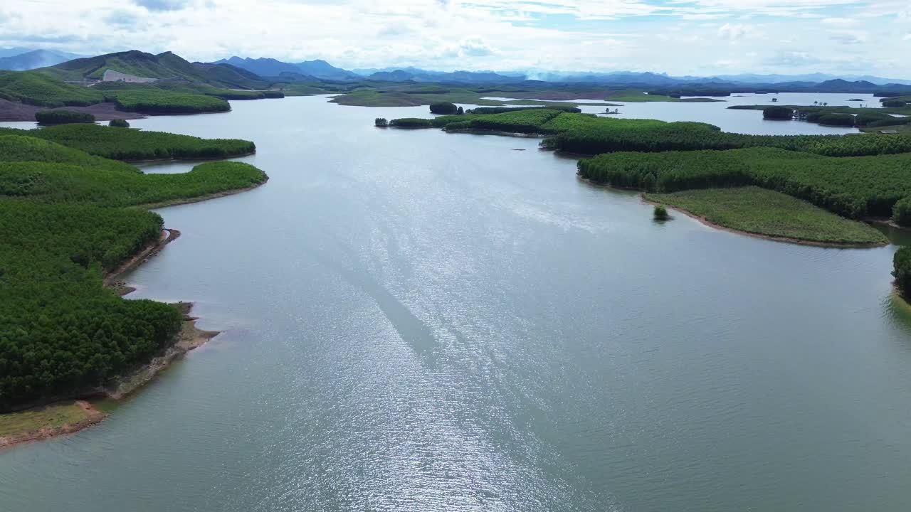 Drone descending above forested islands in a quiet lake surrounded by hills