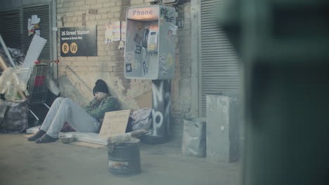 homeless man sleeping near cardboard sign in back alley