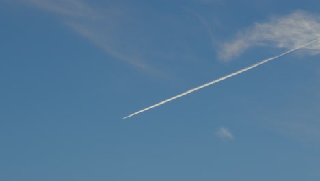 single airplane leaving chemtrail in deep blue sky