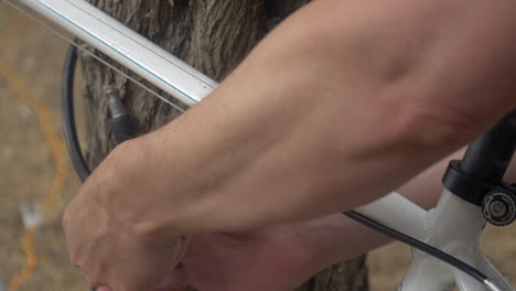 hombre asegurando una bicicleta a un árbol con un cable bloqueable, cerrar