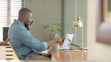 working from home, male professional using smartphone and laptop at desk