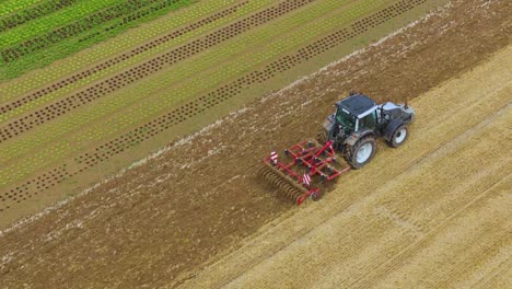 tractor in slow-motion on crop field, high angle view from the corner zooming in