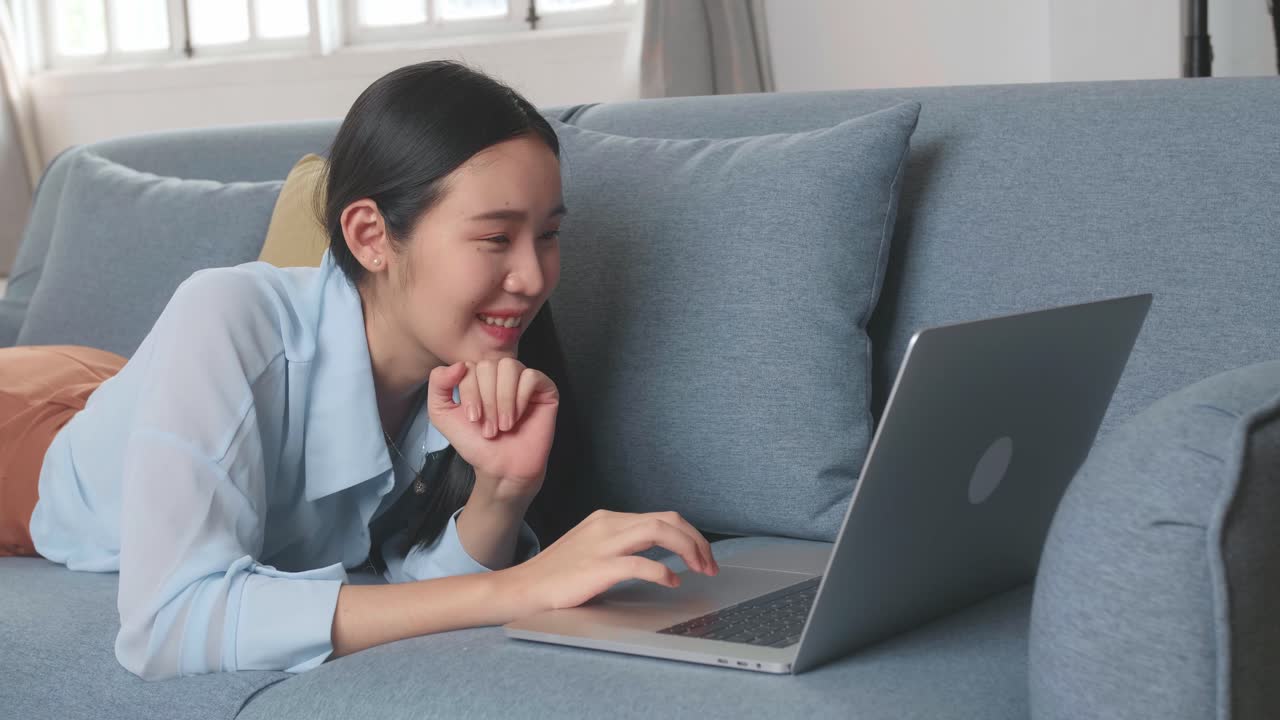 Female Lying On A Sofa And Using Laptop In Living Room, Video In 4K