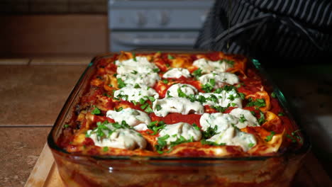 cook pours olive oil over delicious baked lasagna in glass pan, slowmo