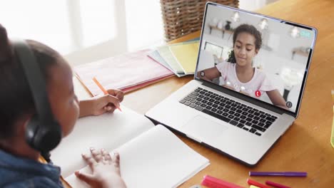 Chica-Afroamericana-Usando-Una-Computadora-Portátil-Para-Videollamada-Con-Un-Amigo-De-La-Escuela-Birracial-En-La-Pantalla