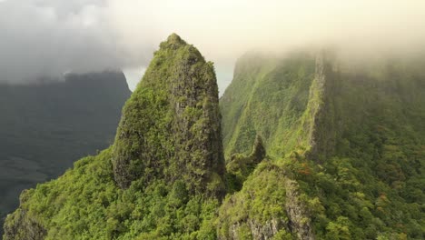 aerial orbiting around dramatic rock formations covered by vegetation and low altitude clouds