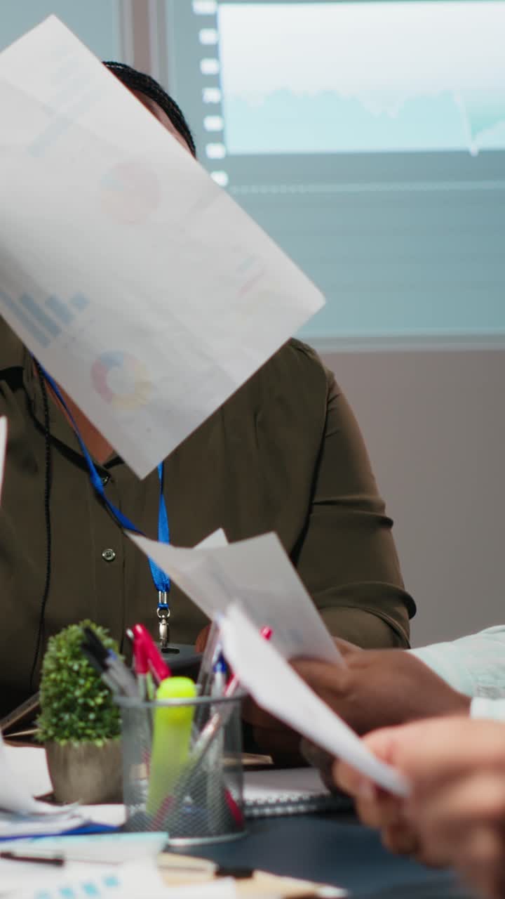 Vertical Video Business partners examining annual sales reports in corporate meeting