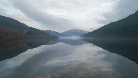 right-to-left aerial view of misty water reflections and mountain scenery