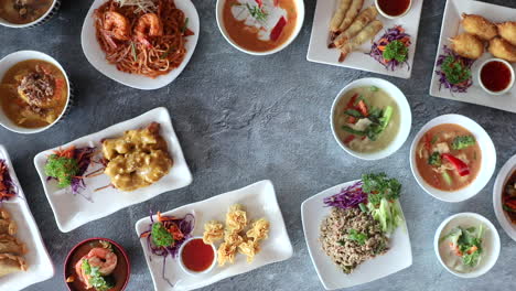 male hand placing down center dish of flat lay into thai cuisine arrangement