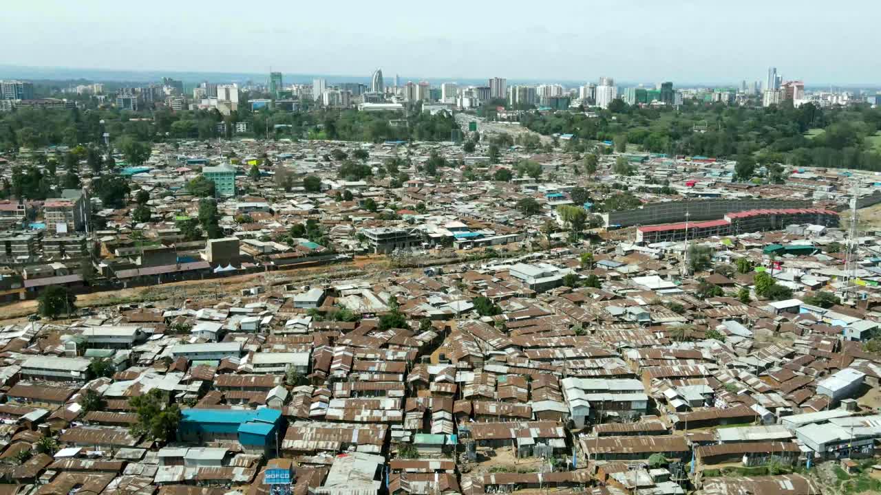 plano general aéreo que muestra el horizonte moderno de nairobi con arquitecturas modernas en el fondo y el distrito suburbano del gueto pobre de kibera en primer plano