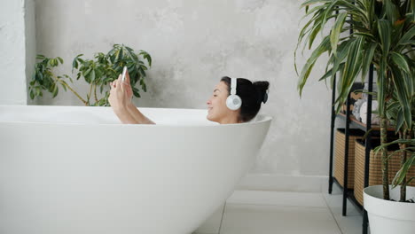 woman taking a selfie in a bathtub with headphones