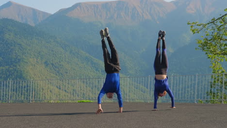 pareja haciendo handstands en las montañas