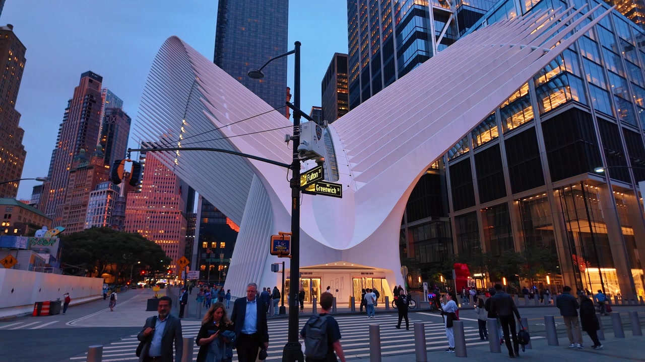 New York, USA, 5 giugno 2026: Ingresso dell'Oculus su Fulton Street, Lower Manhattan, New York. Alette strutturali bianche incontrano un attraversamento pedonale con pedoni, torri di vetro e illuminazione serale.