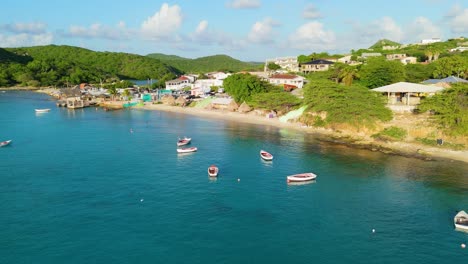 aerial flyover of red white fishing boats anchored in sand off coast of boca sami, curacao