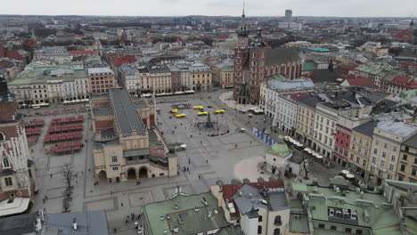 Sobrevuelo-Aéreo-De-La-Plaza-Del-Mercado-Principal-De-Cracovia-Hacia-La-Basílica-De-Santa-María,-Polonia