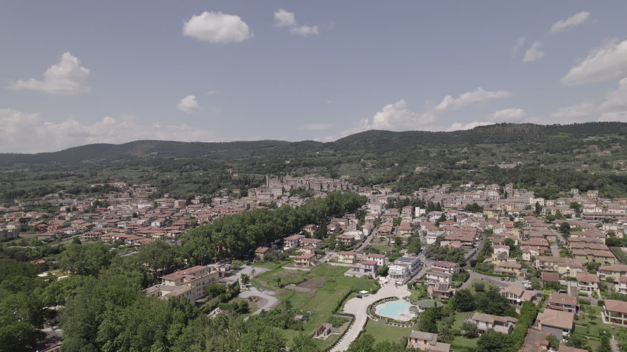 drone disparado volando sobre el lago bolsena en italia viniendo del agua en la antigua ciudad medieval con un castillo y edificios antiguos en la colina en un día soleado