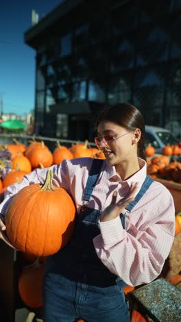 mujer sosteniendo una calabaza en un mercado de otoño