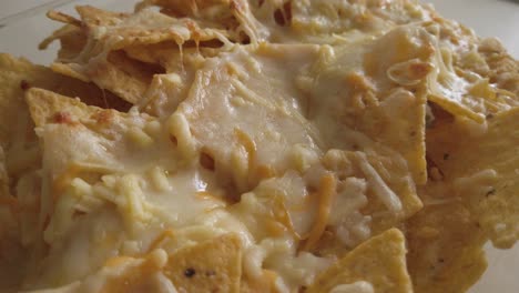 simple nachos with melted white cheese on tortilla chips, closeup