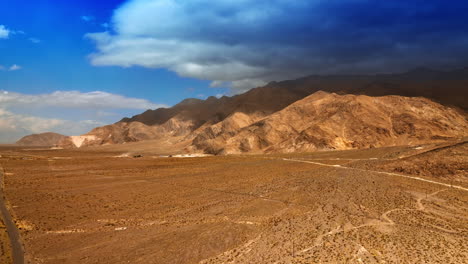 rising above the deserted landscape surrounded by bare mountains. dry hot scenery of nevada. dramatic cloudscape hanging over the mount.