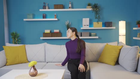 아시안 여성이 슬프게 소파에 앉아 주위를 둘러보기 시작합니다.