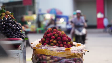 lychee and grapes being sold at street stall next to busy street in southeast asia