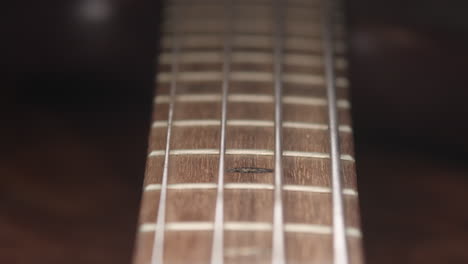 Sliding-forward-along-strings-of-bass-guitar,-slow-push,-close-up