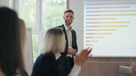 la gente de los negocios está aplaudiendo al joven está mostrando el gráfico de ventas de la conferencia seo e it