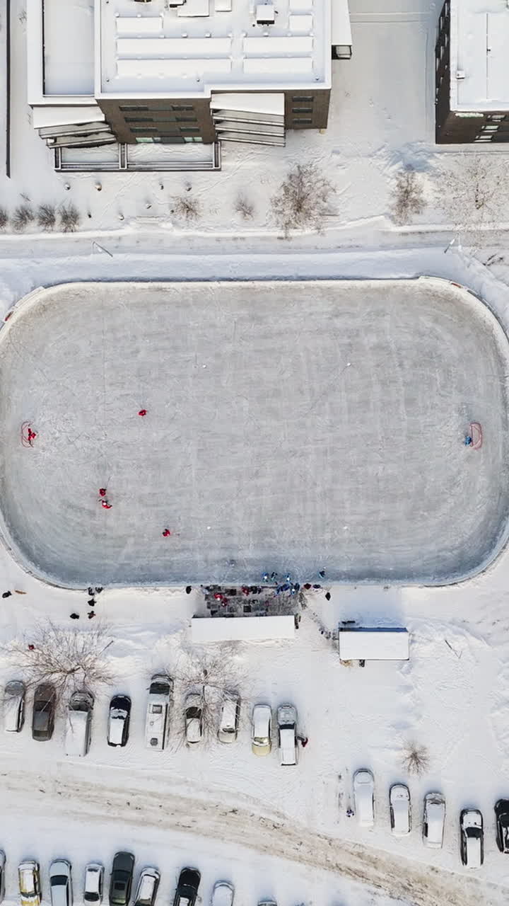 Overhead aerial view rising above ice hockey rink, on a sunny, winter day