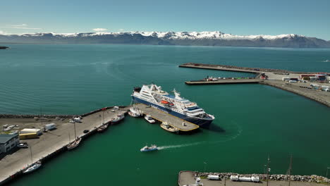 Vista-Del-Puerto-De-Husavik-Pequeño-Barco-Que-Regresa-Del-Mar-A-Lo-Largo-De-Un-Crucero-Gigante