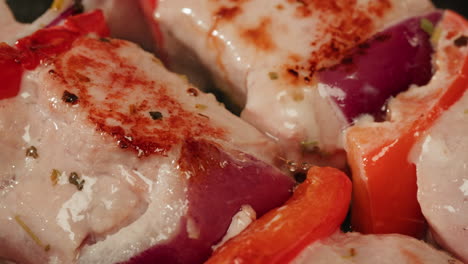 cooking pork skewers with red peppers and onions