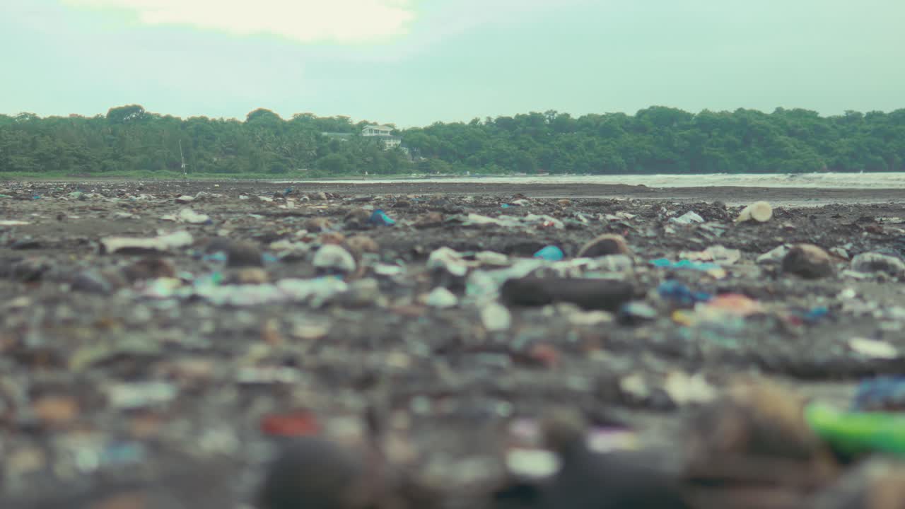 Low angle view of a tropical shoreline covered with plastic waste and debris showing environmental pollution and the impact of human activity on coastal ecosystems