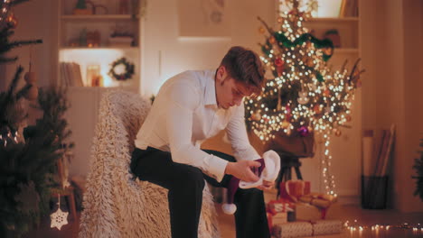 hombre triste sosteniendo el sombrero de papá noel mientras estaba sentado en una silla durante la navidad