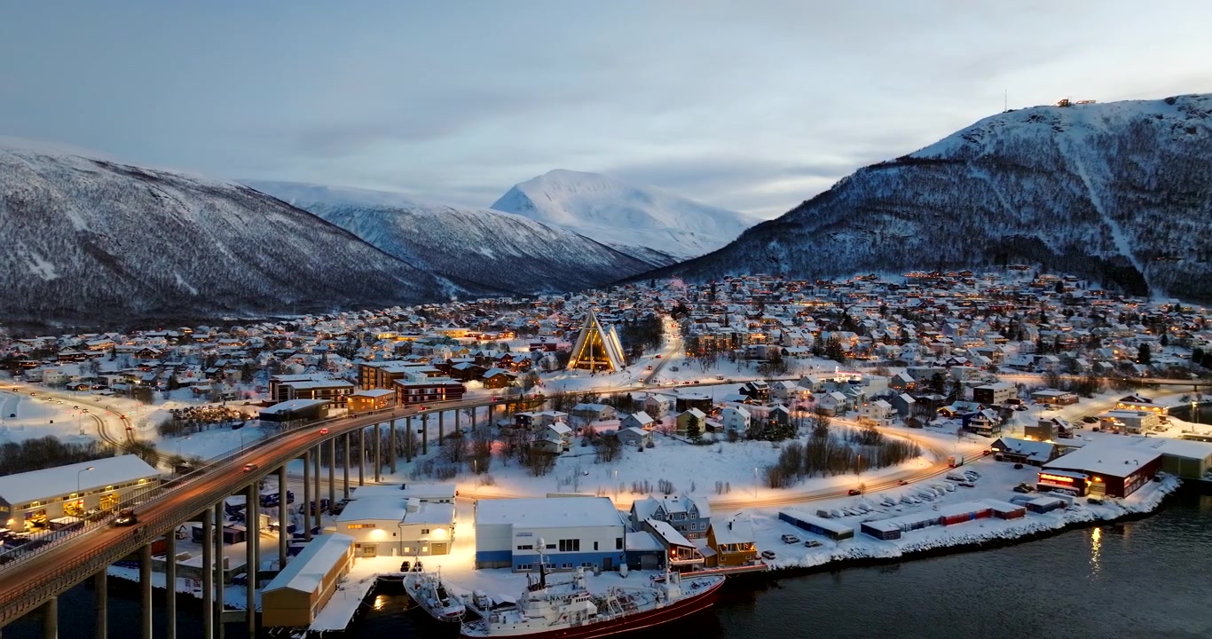 Schneebedeckte Stadt Tromsø, beleuchtete Brücke und Eismeerkathedrale in der blauen Stunde in Norwegen. Panorama-Drohnenansicht, Platz für Text