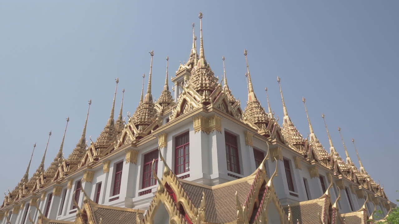 Tilt up and down of a golden and white iron buddhist castle temple still used by monks to meditate in the city of Bangkok in Thailand on a sunny summer day