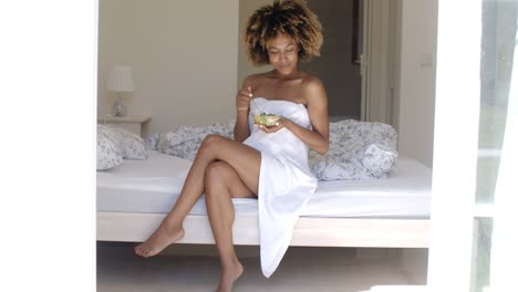 mujer joven en la cama comiendo ensalada de verduras