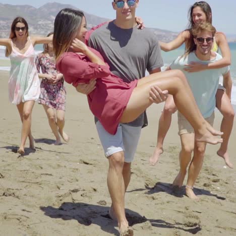 friends carrying each other on beach