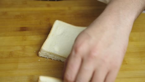 Cutting-bread-on-wooden-cut-board-into-small-square-pieces-for-Caesar-Salad