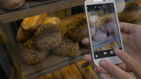 Mujer-Con-Móvil-Tomando-Una-Foto-De-Pan-En-La-Panadería.